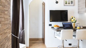 Uma cozinha moderna com televisão de tela plana, um laptop e uma fruteira no balcão.