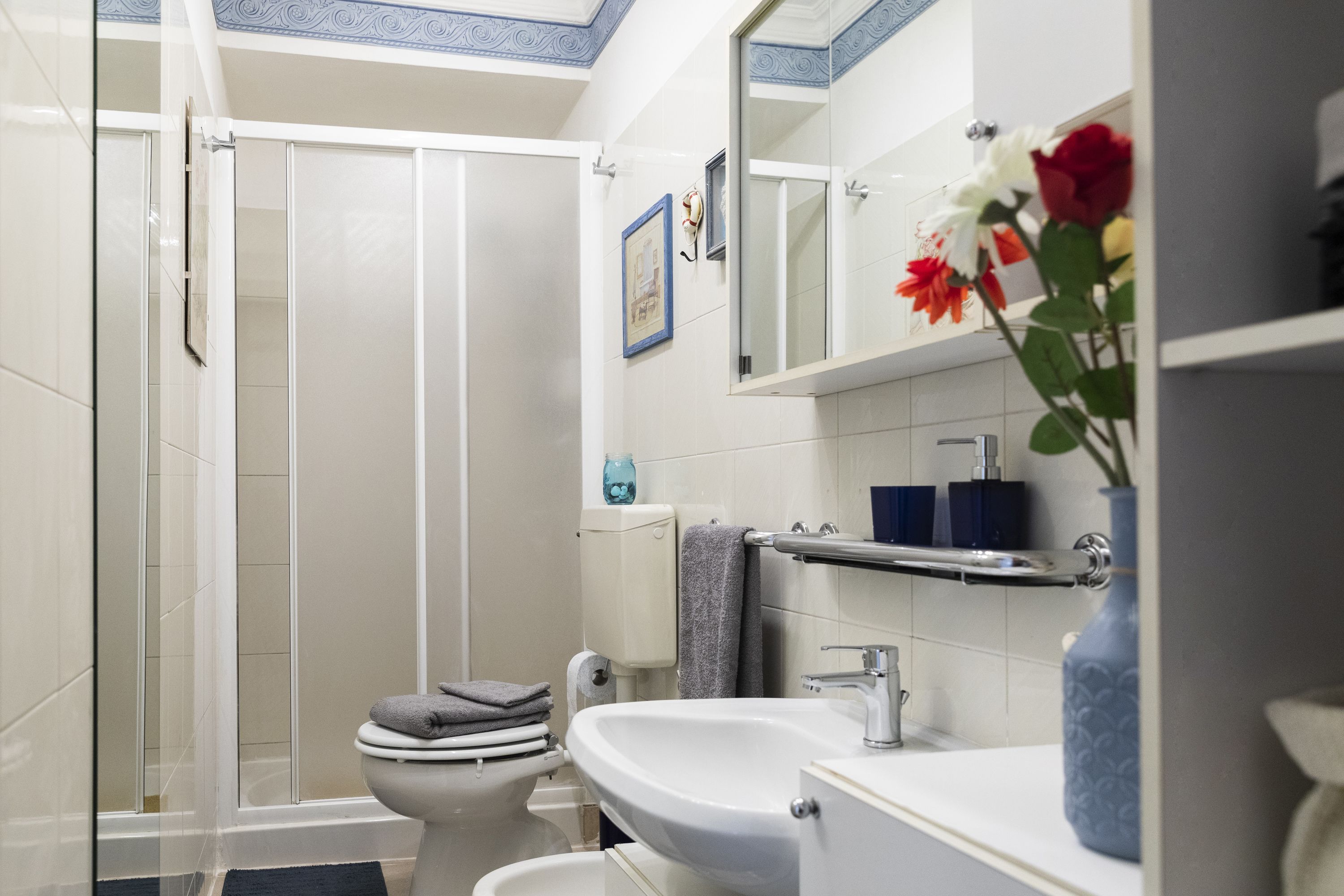 Een moderne badkamer met een douchecabine van glas, een wit wastafelmeubel en een spiegel erboven.