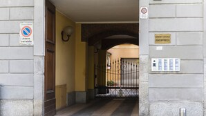 Entrada de um edifício com placa indicando zona proibida a estacionamento e um estúdio jurídico chamado GIOFFREDI.