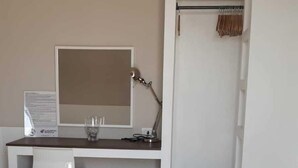 A hotel room with a bed, a desk with a computer, a chair, a trash bin, and a wardrobe. - Gazebo Rooms (Margherita di Savoia)