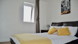 Une chambre à coucher avec un lit, une fenêtre, une table de chevet et un tableau au mur.