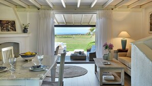 Una sala de estar acogedora con vista al mar, una chimenea y un comedor con una mesa dispuesta para dos.
