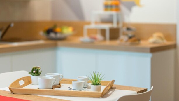 A breakfast tray with cups and a small plant on a table in a modern kitchen setting. - Le Mie Città (Pescara)
