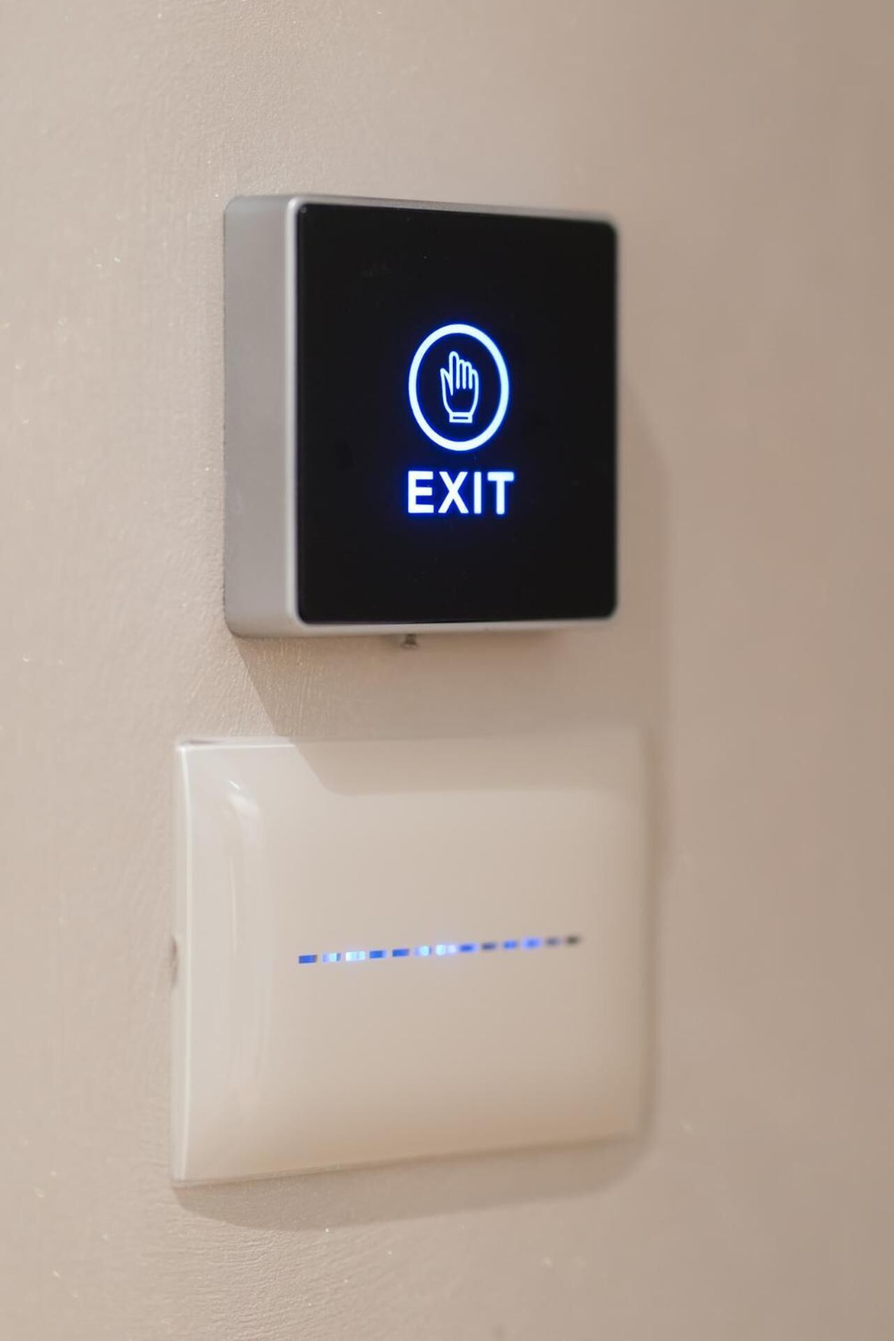 An exit sign with a hand symbol and the word "EXIT" on a wall-mounted panel.