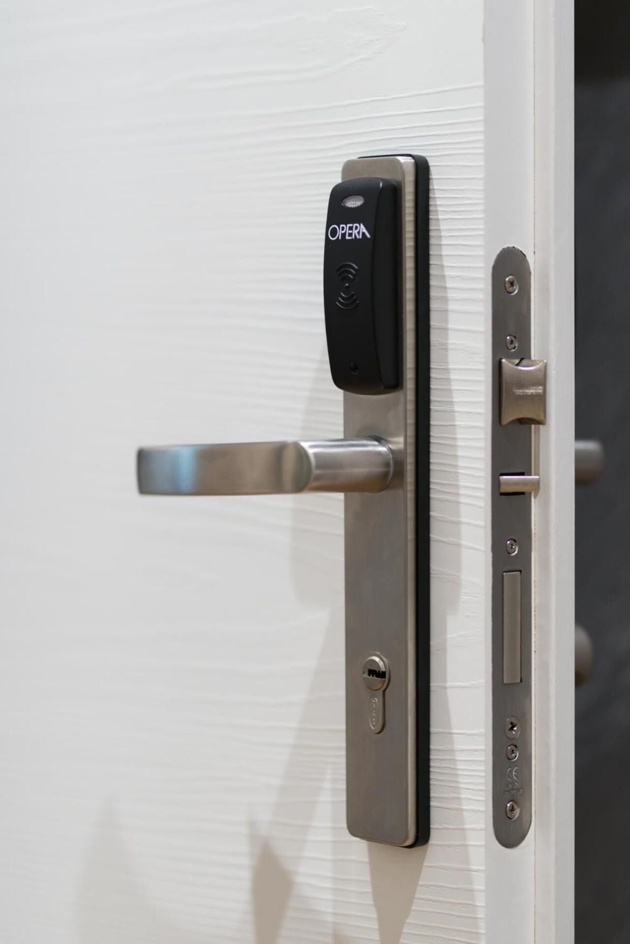 A modern door with a keycard reader labeled "OPERA" and a push bar.