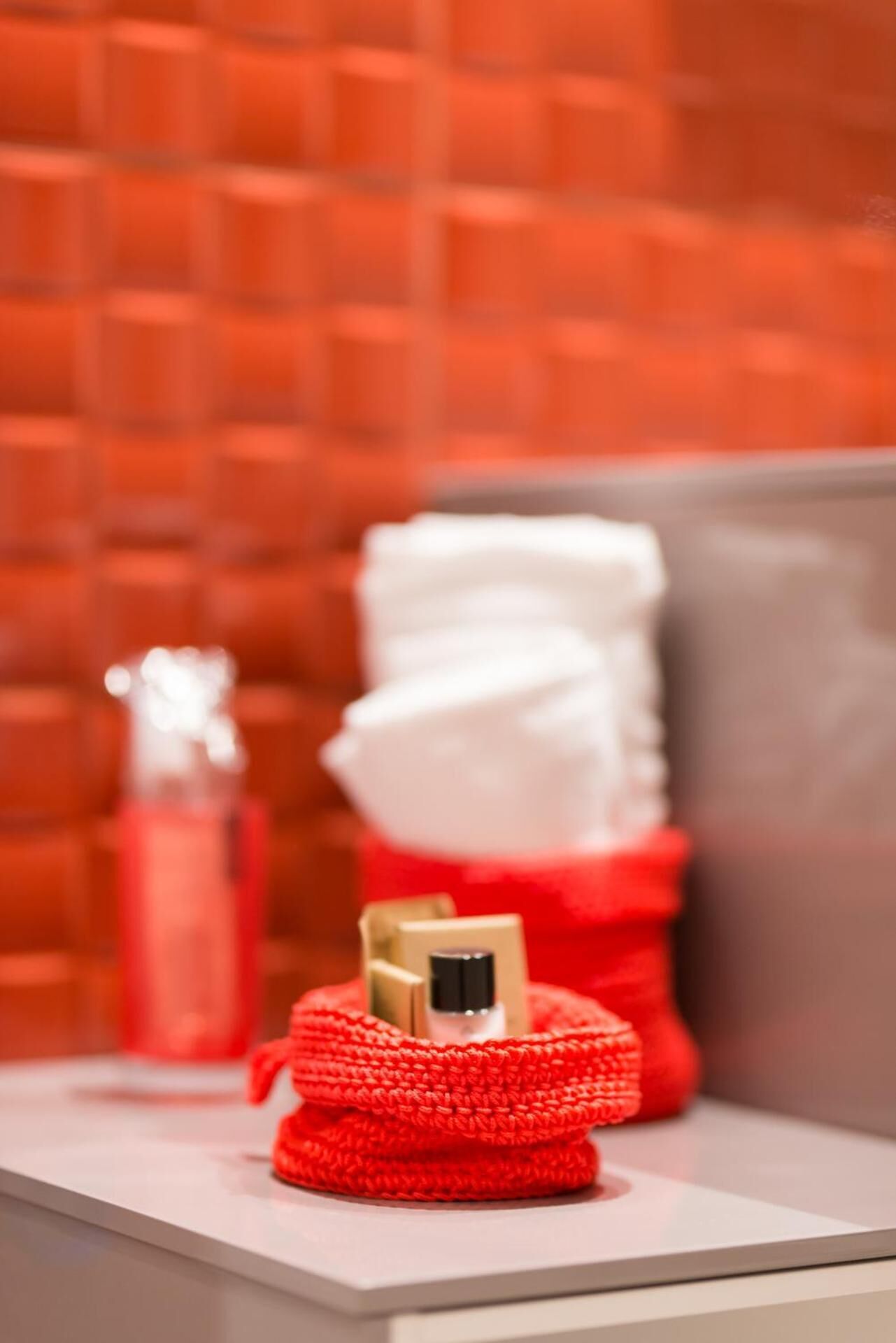 Un article tricoté rouge sur une surface blanche, avec un arrière-plan flou.