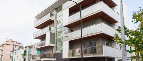 Un edificio residencial de varios pisos con balcones, una farola y un coche estacionado.