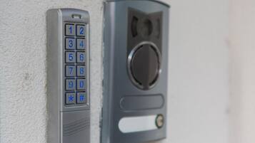 A wall-mounted intercom system with a numeric keypad and a speaker grille.