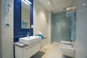A modern bathroom with a white sink, a mirror, a towel rack, and a glass shower enclosure. - Le Mie Città (Pescara)