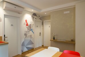 A modern hotel room with a wooden floor, a white bed, a red chair, and a small table with a vase of flowers. - Le Mie Città (Pescara)