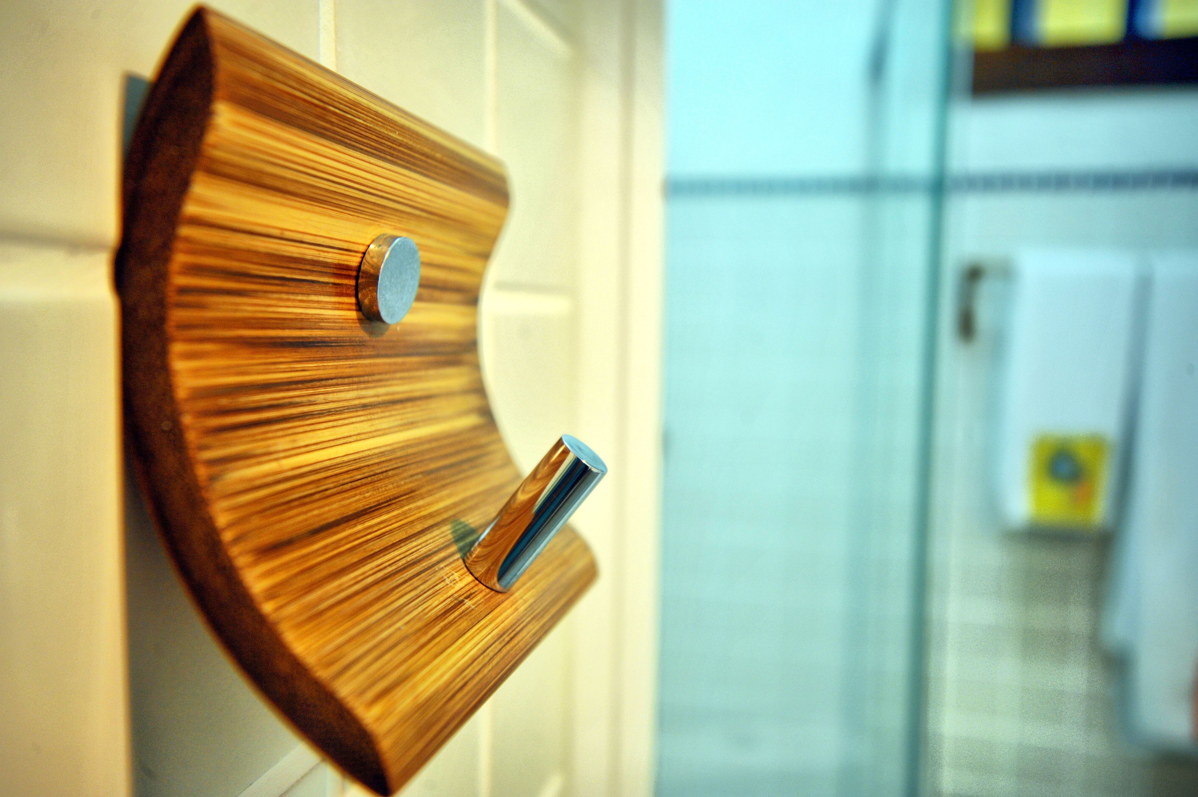 Ein aus Holz gefertigter, an der Wand befestigter Handtuchhalter mit zwei Metallhaken.