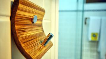 Ein aus Holz gefertigter, an der Wand befestigter Handtuchhalter mit zwei Metallhaken.