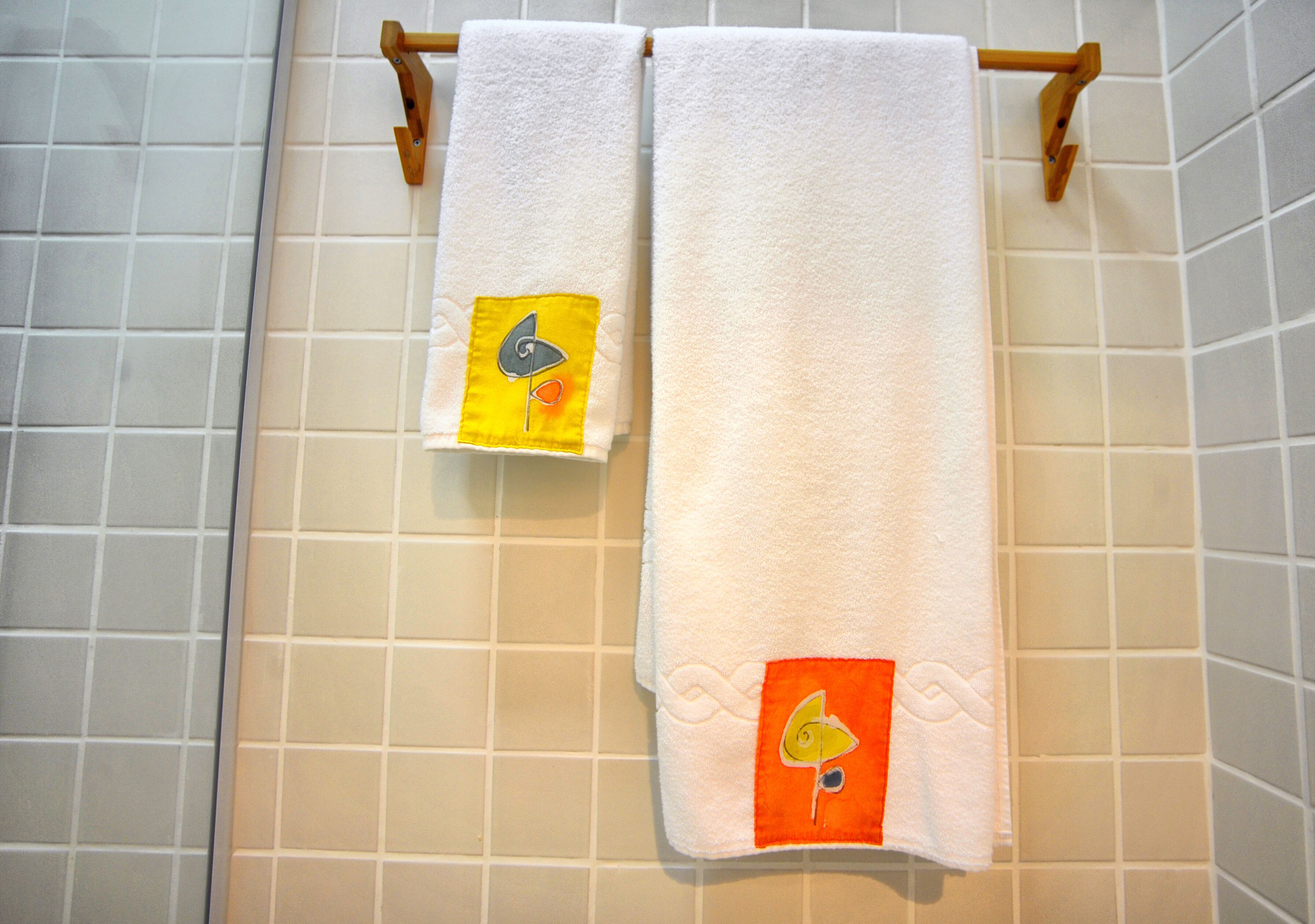 Twee handdoeken hangen aan een rek in een betegelde badkamer.