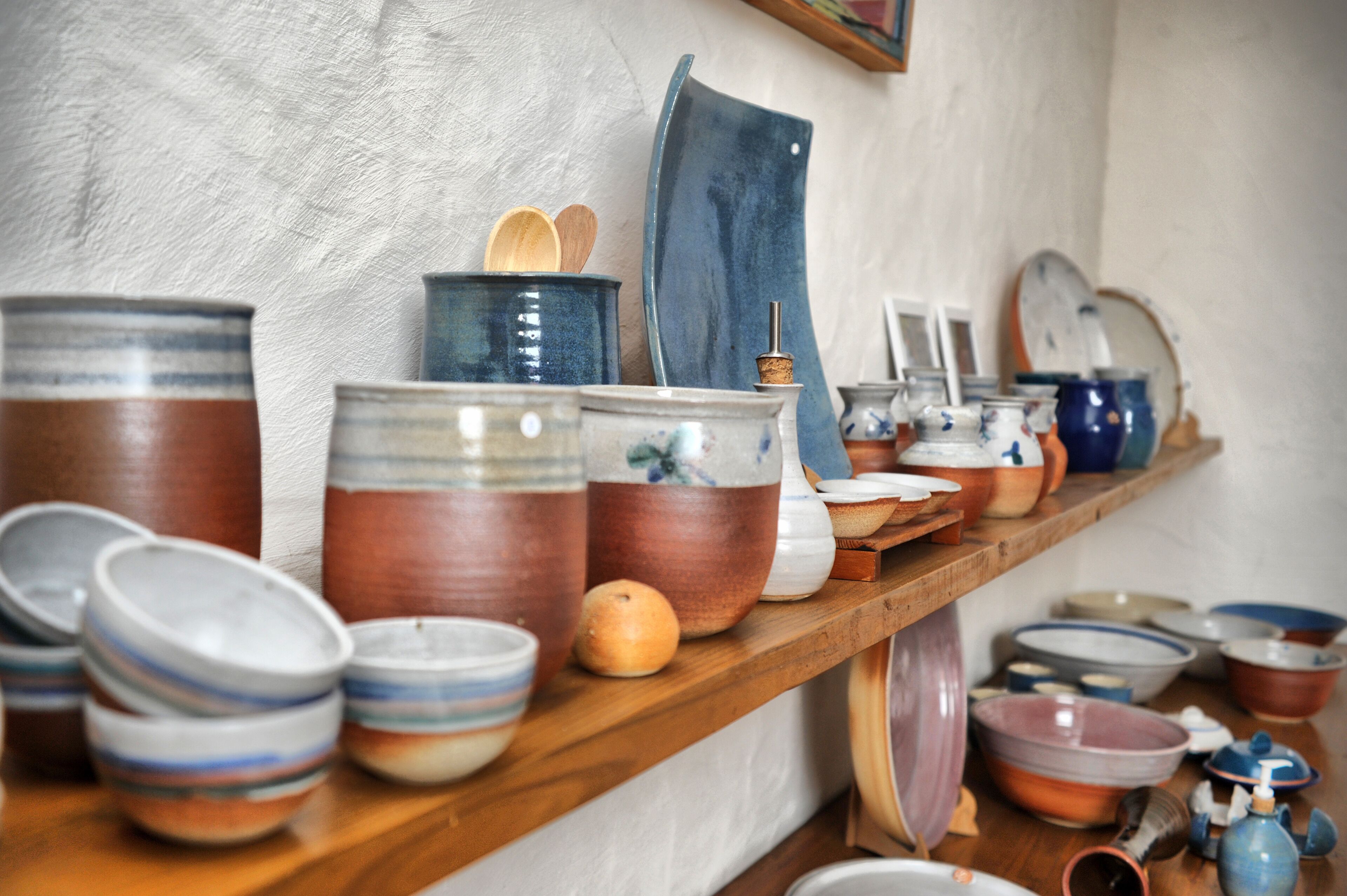 A wooden shelf with various ceramic containers and bowls.