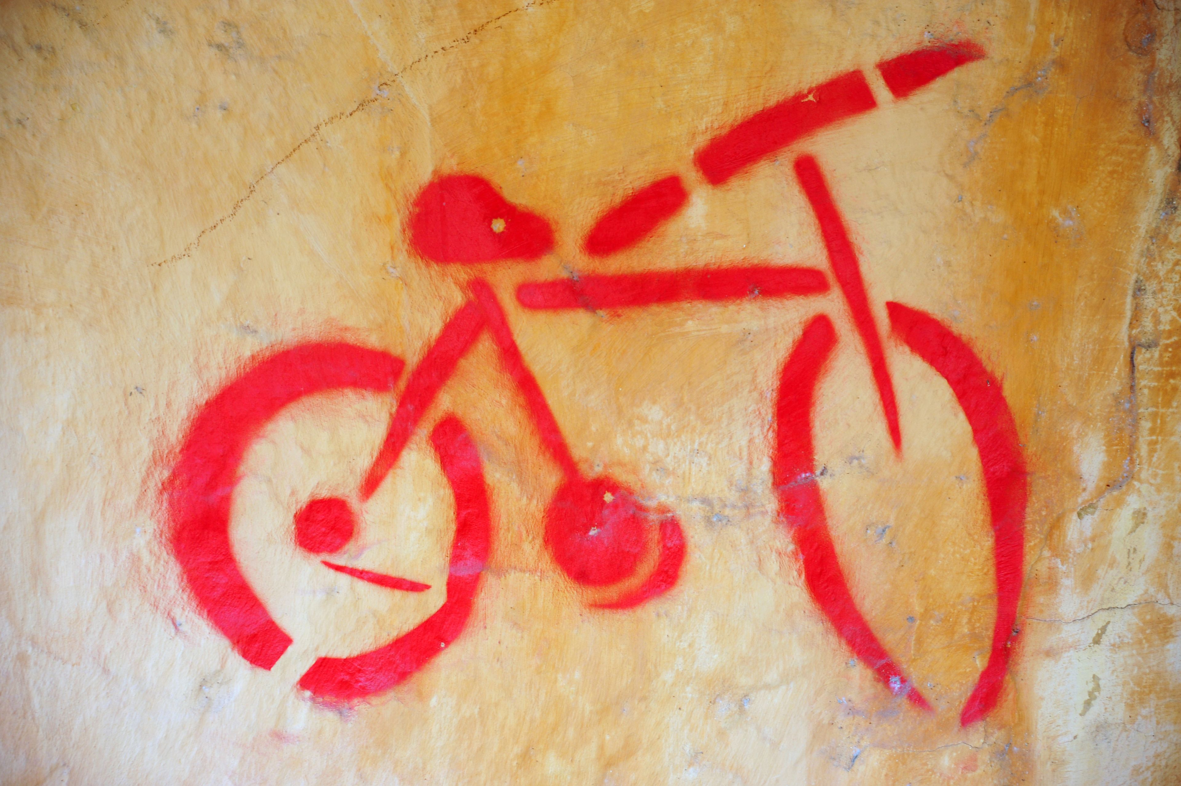 Un símbolo de bicicleta roja sobre una pared con textura.