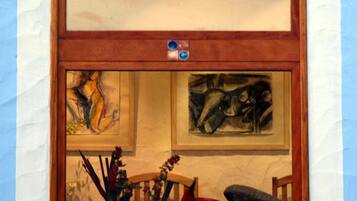 Ein Fenster mit Holzrahmen, eine Pendelleuchte und zwei gerahmte Kunstwerke darunter.