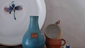 Un jarrón de cerámica, una taza y un plato con diseño de mariposa sobre una mesa.