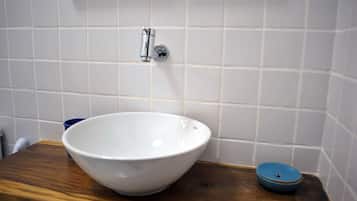 A white ceramic bowl on a wooden countertop with a blue lid beside it.