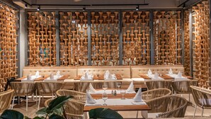 A restaurant with a unique wall of terracotta pots, wicker furniture, and a cozy seating area.