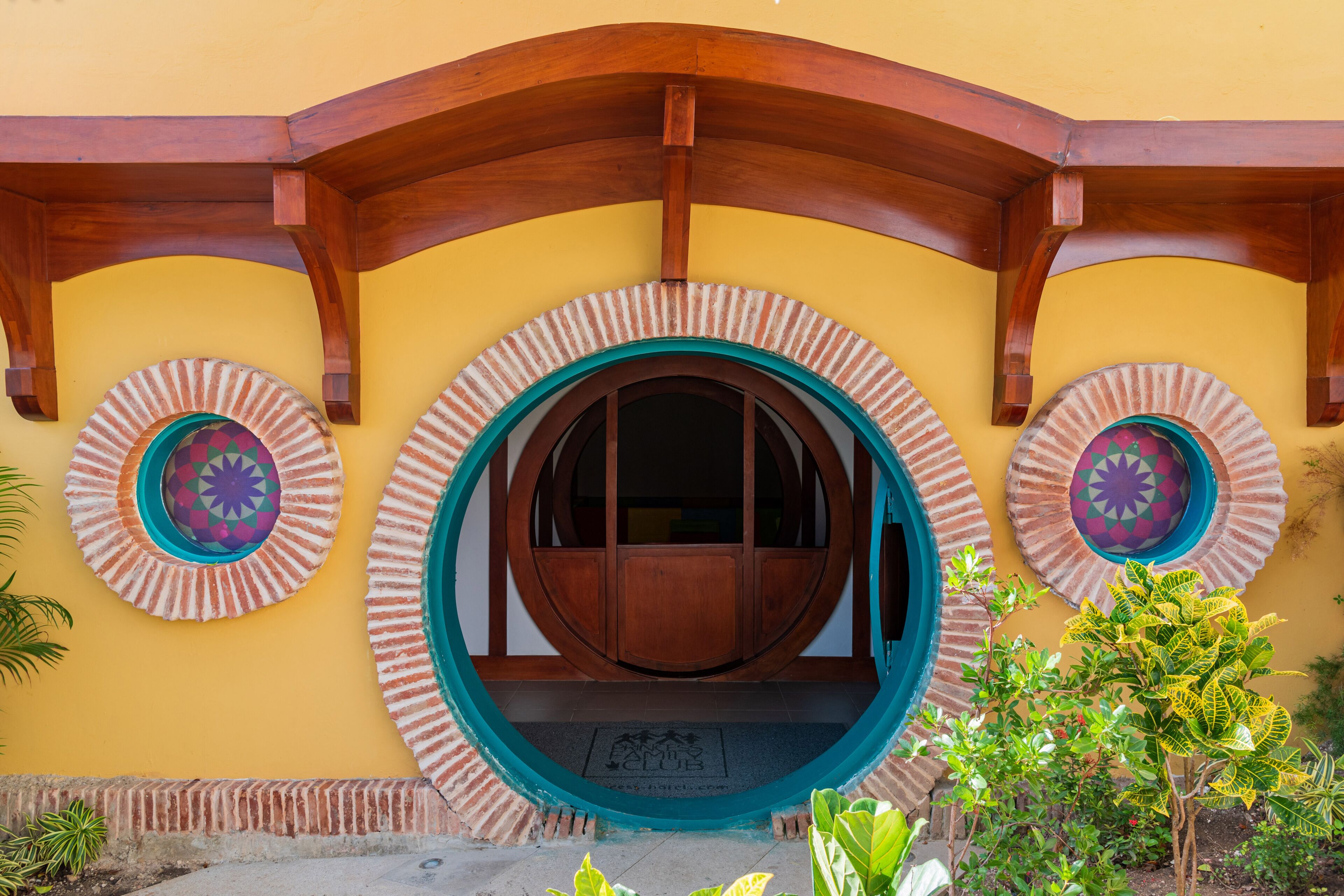 Une entrée d’immeuble avec une arche en bois et trois portes d’entrée circulaires ornées de motifs décoratifs.
