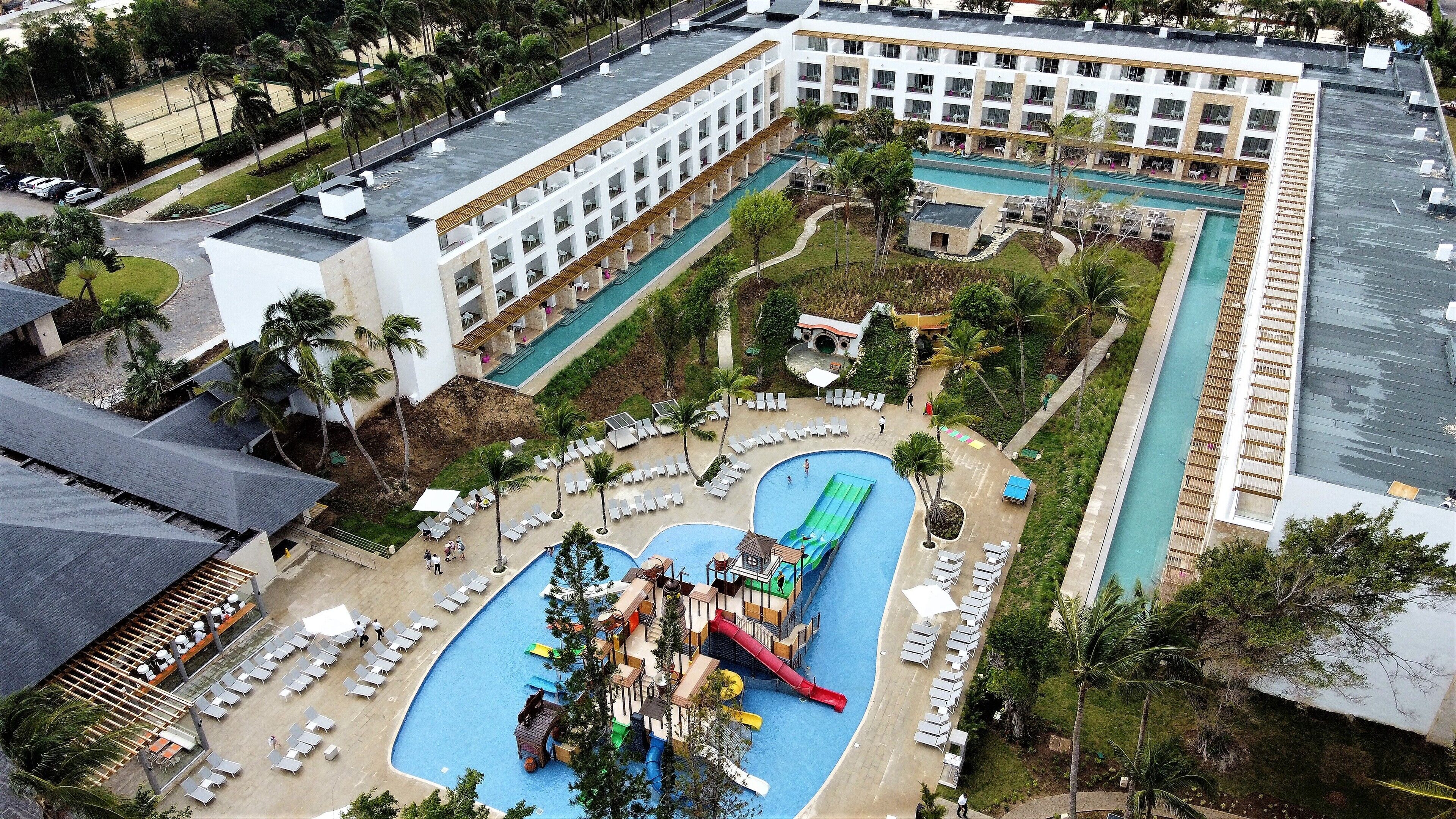 A resort with multiple swimming pools, a water park, and a large building with balconies.
