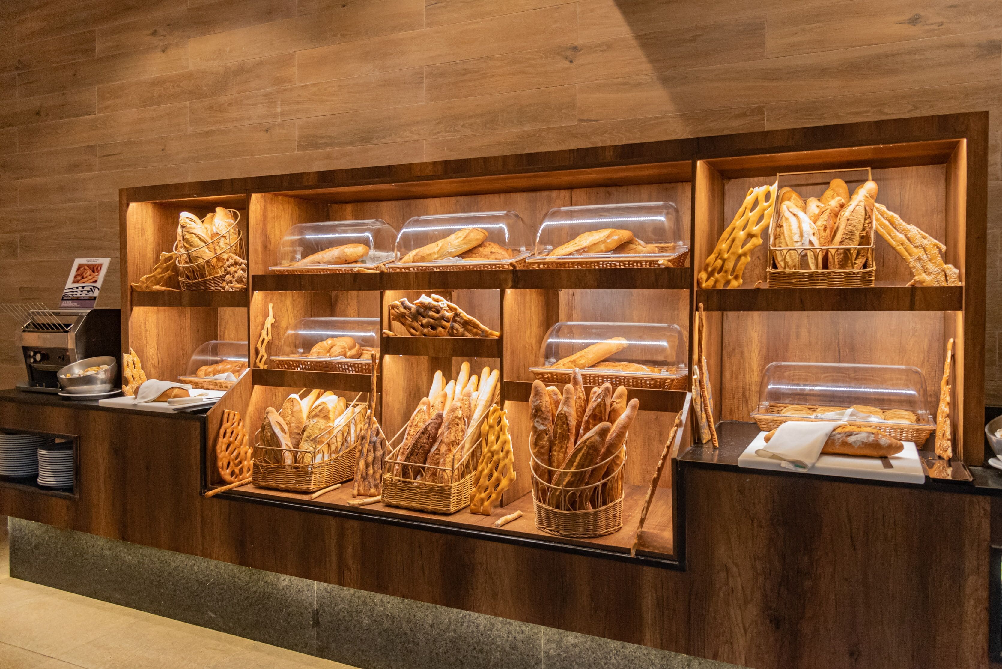 Une vitrine de boulangerie présentant divers pains et pâtisseries dans des paniers et des récipients.