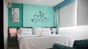 Quarto com cama, mesas de cabeceira, uma cadeira e uma parede decorada.