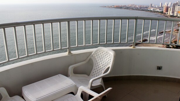 Uma varanda com vista para o mar e para a paisagem urbana.