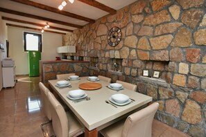 Un coin repas avec un mur en pierre, une horloge et un réfrigérateur vert.