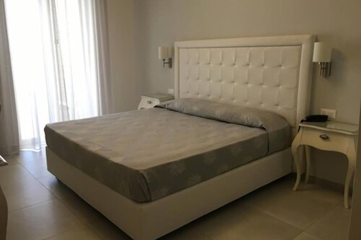 Un dormitorio moderno con una cama grande, una mesita de noche y una mesilla.