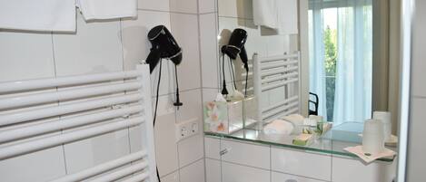 Une salle de bain avec un lavabo en verre, un miroir, un porte-serviettes et un sèche-cheveux.