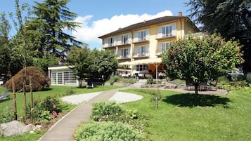 Un hotel con jardín, mobiliario exterior y un edificio con varios balcones.