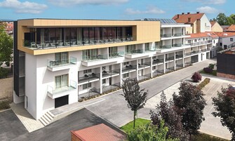 Un hotel moderno con varios balcones, grandes ventanales y techo plano.
