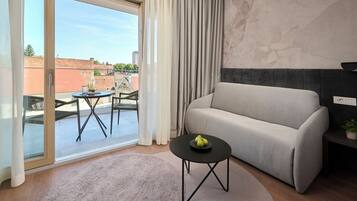 Una sala de estar moderna con un sofá, una mesita baja con fruta y vistas a la ciudad a través de un ventanal corredero.