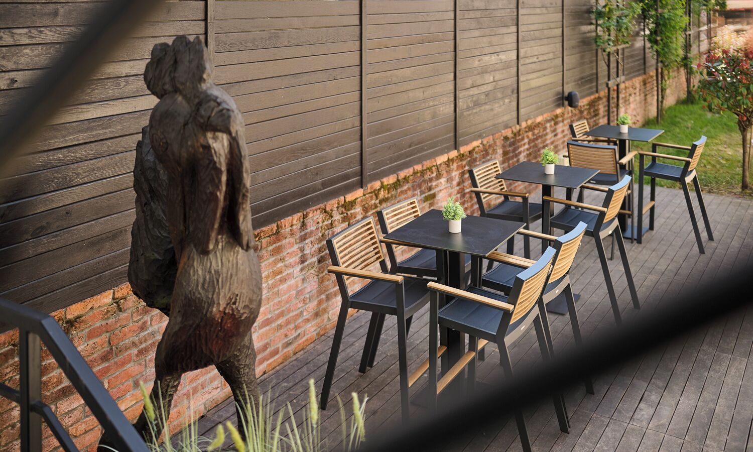 Un patio con posti a sedere all'aperto, un muro in mattoni e una scultura in legno.