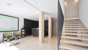 Un interior moderno con escalera, mostrador de recepción y zona de estar.
