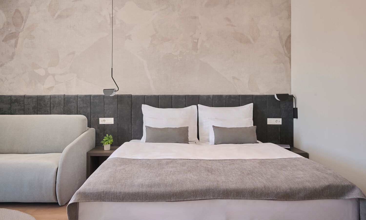Un dormitorio moderno con una cama, un sofá y una mesita de noche.