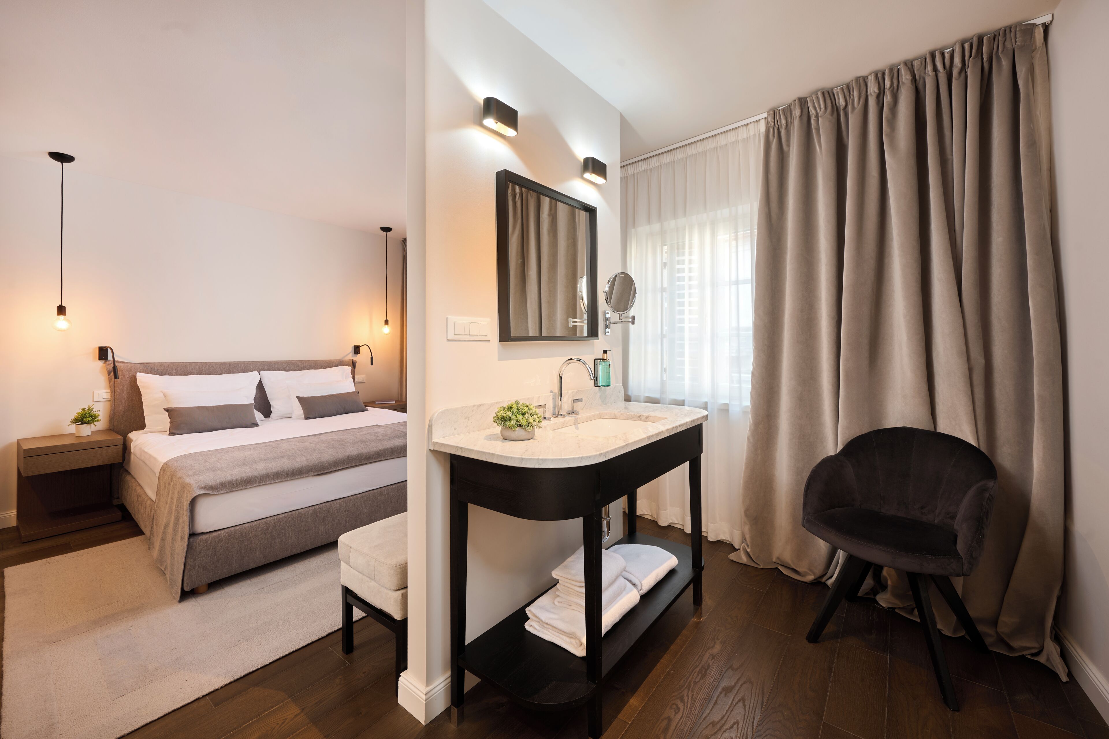 Un dormitorio moderno con cama, mesita de noche y baño con lavabo y espejo.