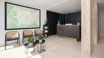 A reception area with a large map, three wicker chairs, a reception desk, and potted plants.