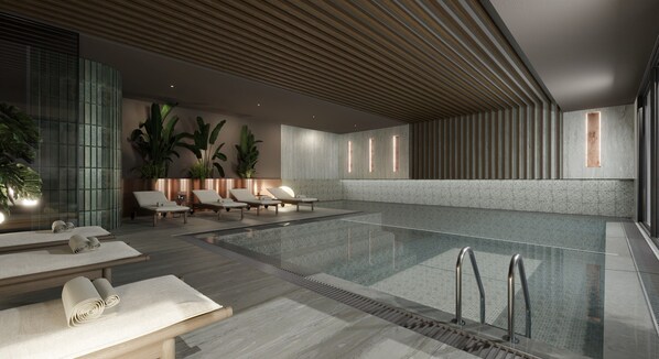 A modern indoor pool area with lounge chairs, a pool, and a ceiling with wooden slats.