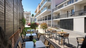 Un patio con mobiliario exterior, un muro de ladrillo y un edificio con balcones.