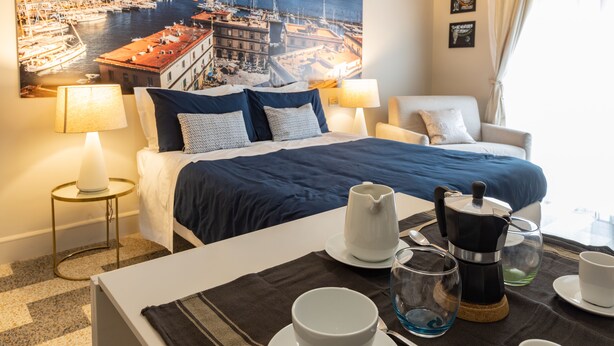 A hotel room with a bed, a dining table set with a coffee pot, cups, and a glass. - Art&B.E.D.S. (Naples)