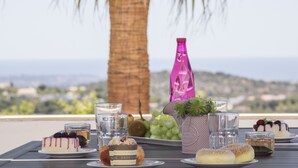 A table with desserts, drinks, and a bottle on a terrace with a view. - Villa Angel | 2 Bedrooms | Panoramic Views | Parragil (Loulé)
