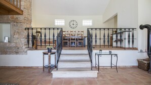 A staircase with a clock, stone walls, and a view to the upper floor. - Villa Angel | 2 Bedrooms | Panoramic Views | Parragil (Loulé)
