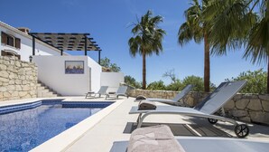 A pool area with lounge chairs, a pergola, and a stone wall. - Villa Angel | 2 Bedrooms | Panoramic Views | Parragil (Loulé)
