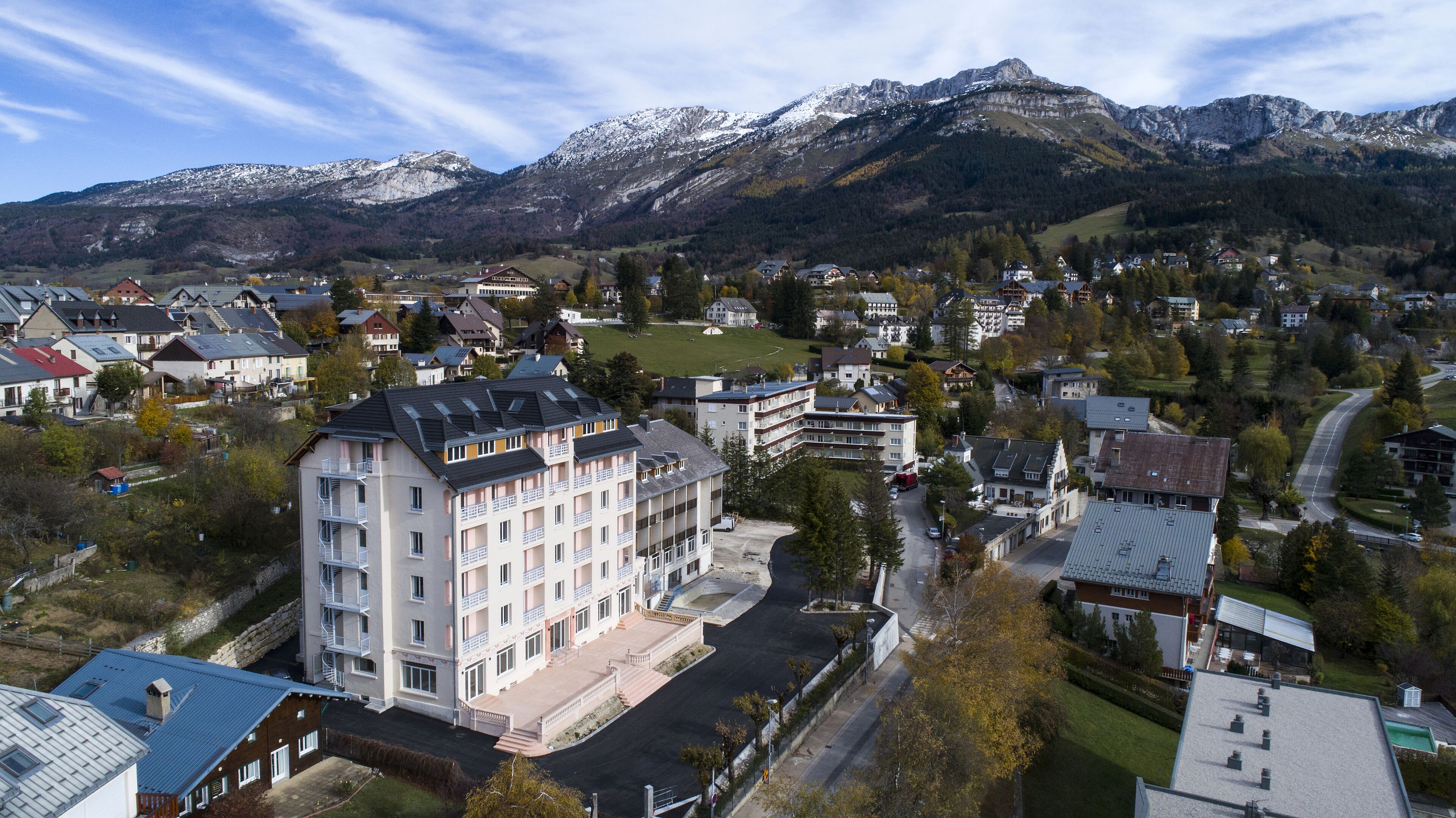 Un hotel de varios pisos con balcones, rodeado por un paisaje montañoso.