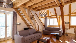 A spacious living area with a wooden staircase, two sofas, a coffee table, and a floor lamp. - Residence Le Splendid (Villard-de-Lans)
