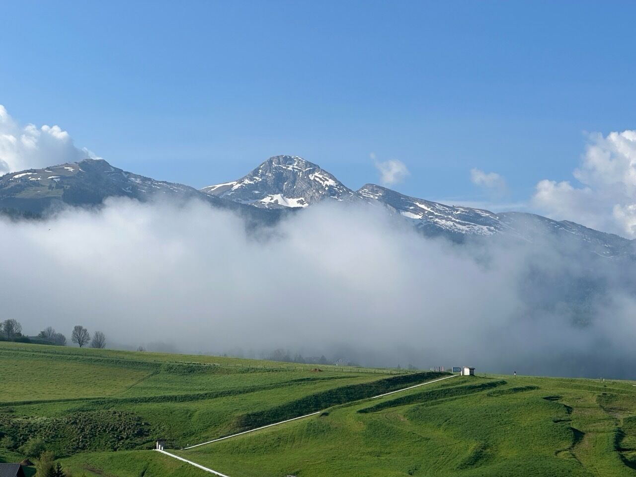 Un paysage montagneux avec des champs verdoyants et un ciel dégagé.