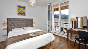 A bedroom with a large bed, a desk, a chair, a window with a view, and a painting on the wall. - Residence Le Splendid (Villard-de-Lans)