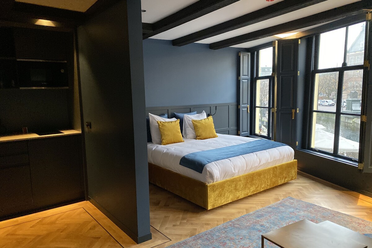 Une chambre moderne avec un lit, un bureau et de grandes fenêtres.